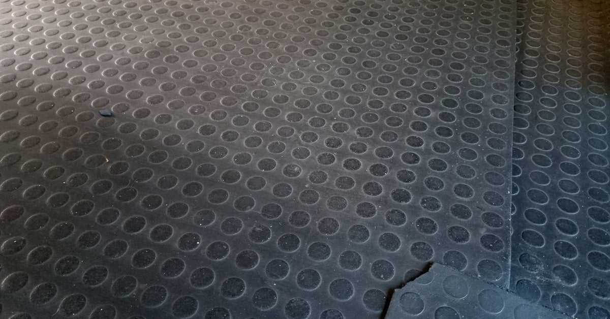 There is a black floor mat with visible dirt on its surface, and there are two other mats underneath the top one.